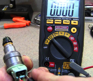 In this picture, a fuel injector is being tested for electrical resistance with an ohmmeter. While the injector shown here has been removed from the vehicle, this type of testing can be done without doing so.