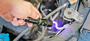 In this picture, an ultraviolet flashlight is being used to detect the presence of leak tracing dye in an air conditioning system. Areas where the dye has leaked out of the system can be determined because the dye is designed to glow when subject to UV rays.