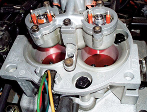 Shown here is a throttle body assembly without fuel rails. Instead, fuel injectors are mounted in the two circular pods at the top. In this photo, electrical connectors have been removed.)